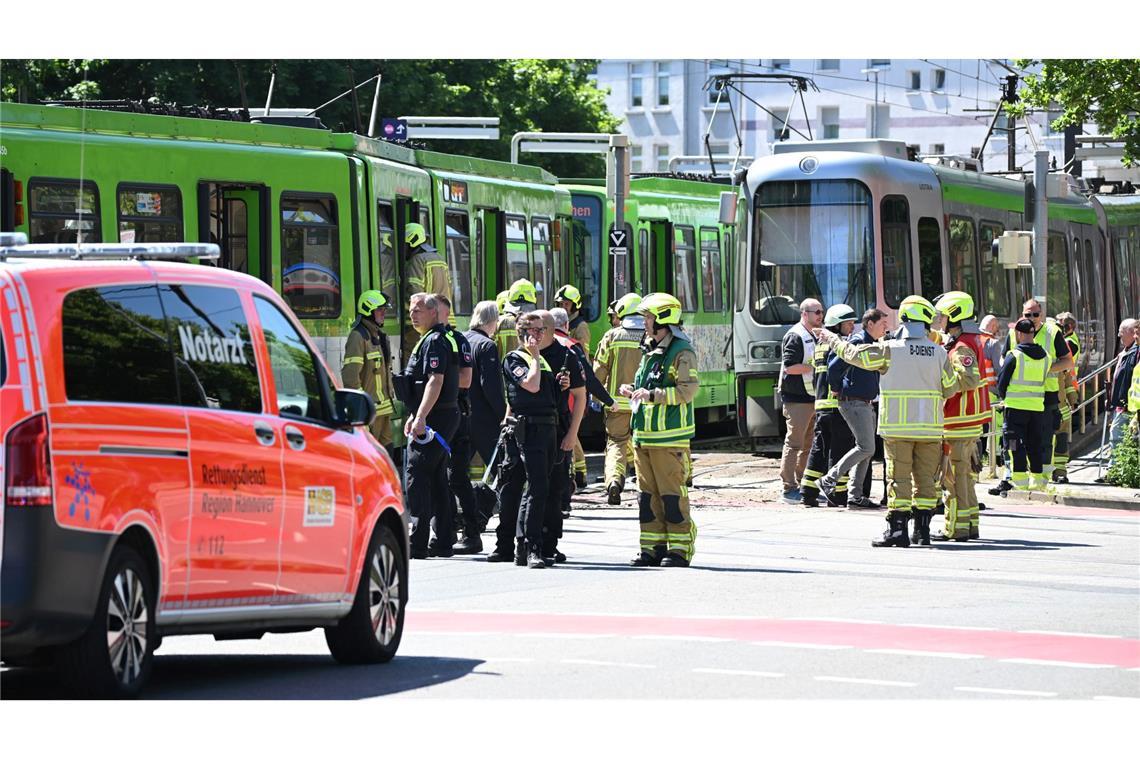 Einsatzkräfte von Polizei und Feuerwehr stehen nach einem Unfall neben zwei Stadtbahnen.