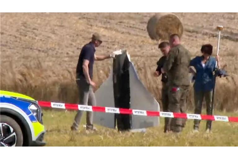 Einsatzkräfte von Polizei und Militärpolizei sichern Teile einer beschädigten Drohne.