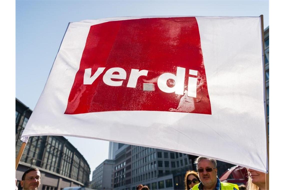 Ein Teilnehmer eines Streiks schwenkt eine Flagge der Gewerkschaft Verdi. Foto: Christophe Gateau/dpa/Symbolbild