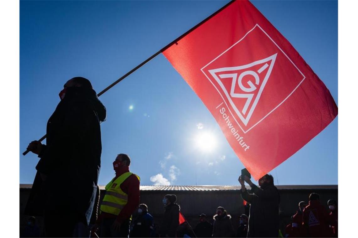 IG Metall wehrt sich gegen geplanten Stellenabbau bei Bosch Ein Teilnehmer eines Warnstreicks schwenkt eine Fahne mit dem Logo der IG Metall. Foto: Nicolas Armer/dpa/Symbolbild