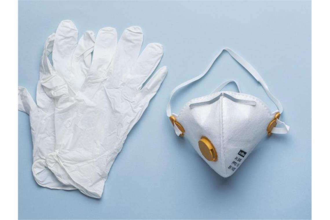 Einweghandschuhe und eine Atemschutzmaske auf einem Tisch. Foto: Christian Beutler/KEYSTONE/dpa/Archivbild