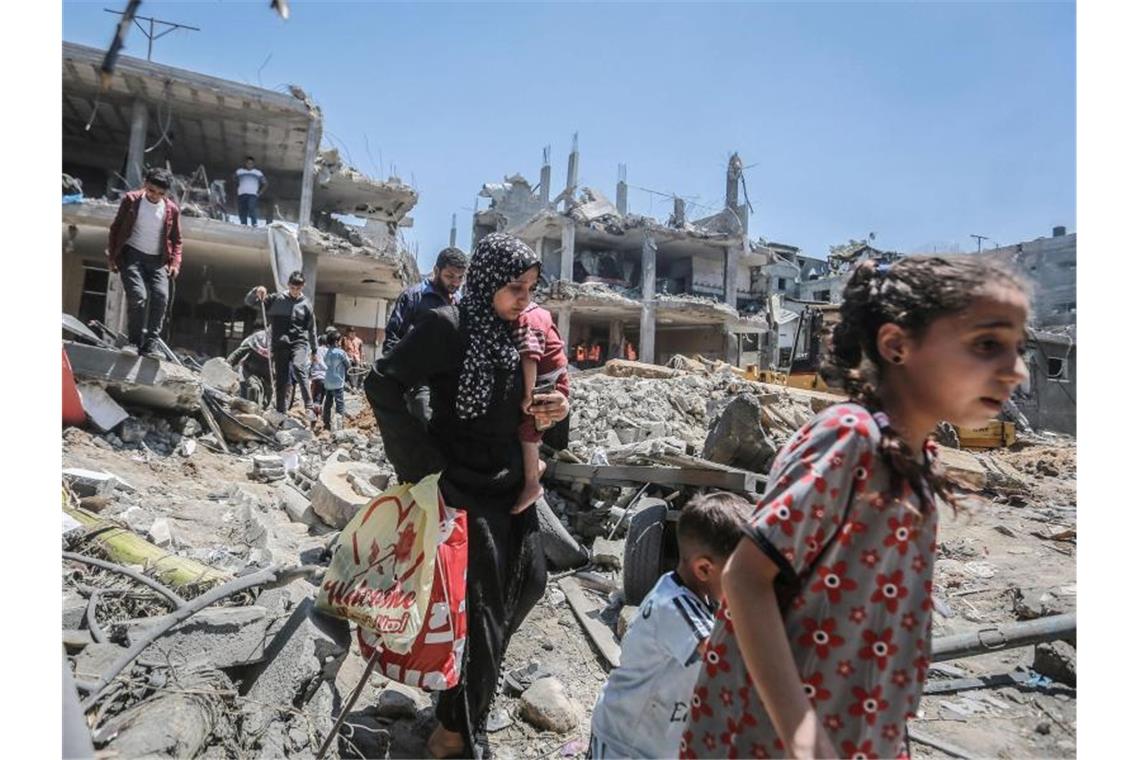 Israel greift Hamas-Tunnel an - Feuerpause nicht in Sicht Einwohner des Gazastreifens gehen durch die Trümmer, die ein israelischer Luftangriff hinterlassen hat. Foto: Mohammed Talatene/dpa