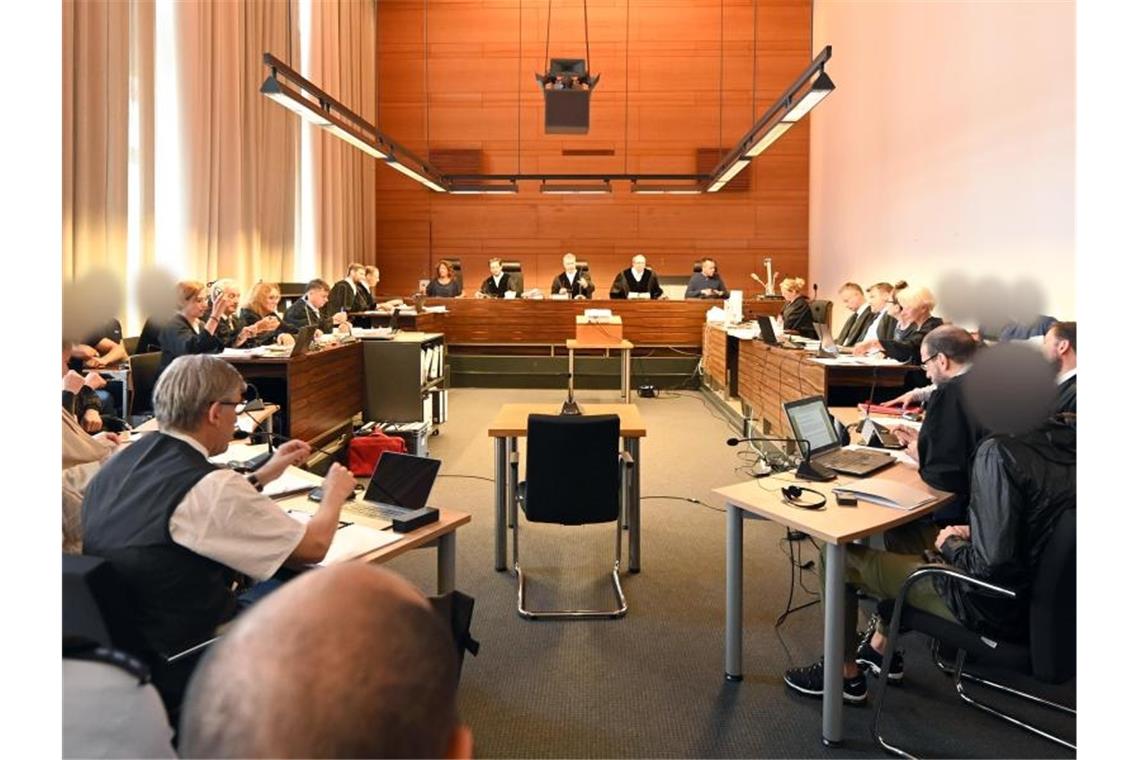 Prozess um Gruppenvergewaltigung: Opfer bei Tat verletzt Elf Angeklagte und Justizbeamte sitzen im Landgericht seitlich hinter den Anwälten. Foto: Patrick Seeger/dpa/Archivbild