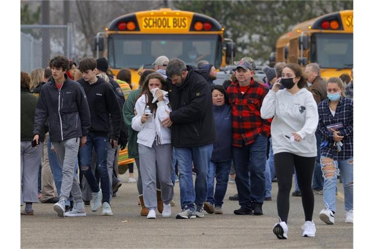 Eltern verlassen mit ihren Kindern einen Parkplatz, wo sich viele Schüler nach einer Schießerei an der Oxford High School im US-Bundesstaat Michigan versammelt haben. Foto: Eric Seals/Detroit Free Press via AP/dpa