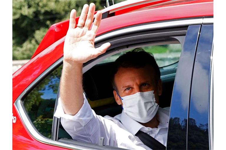 Emmanuel Macron gibt sich die Ehre: Der Präsident von Frankreich winkt auf der 18. Etappe aus einem Auto. Foto: Thomas Samson/AFP/dpa