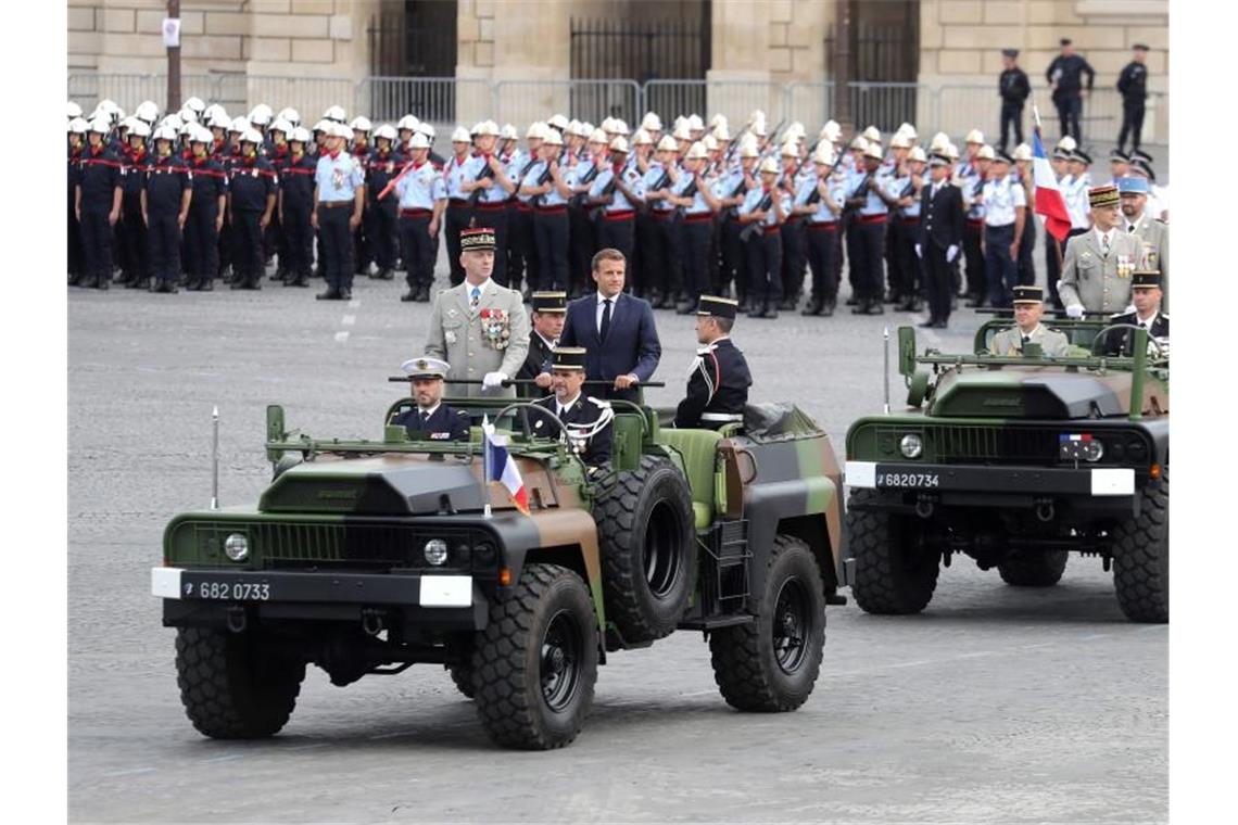 Präsident Macron bereitet Franzosen auf harte Zeiten vor Emmanuel Macron, Präsident von Frankreich, und Francois Lecointre, Chef des französischen Generalstabs, inspizieren Truppen vor der Militär-Feier. Foto: Ludovic Marin/AFP/dpa