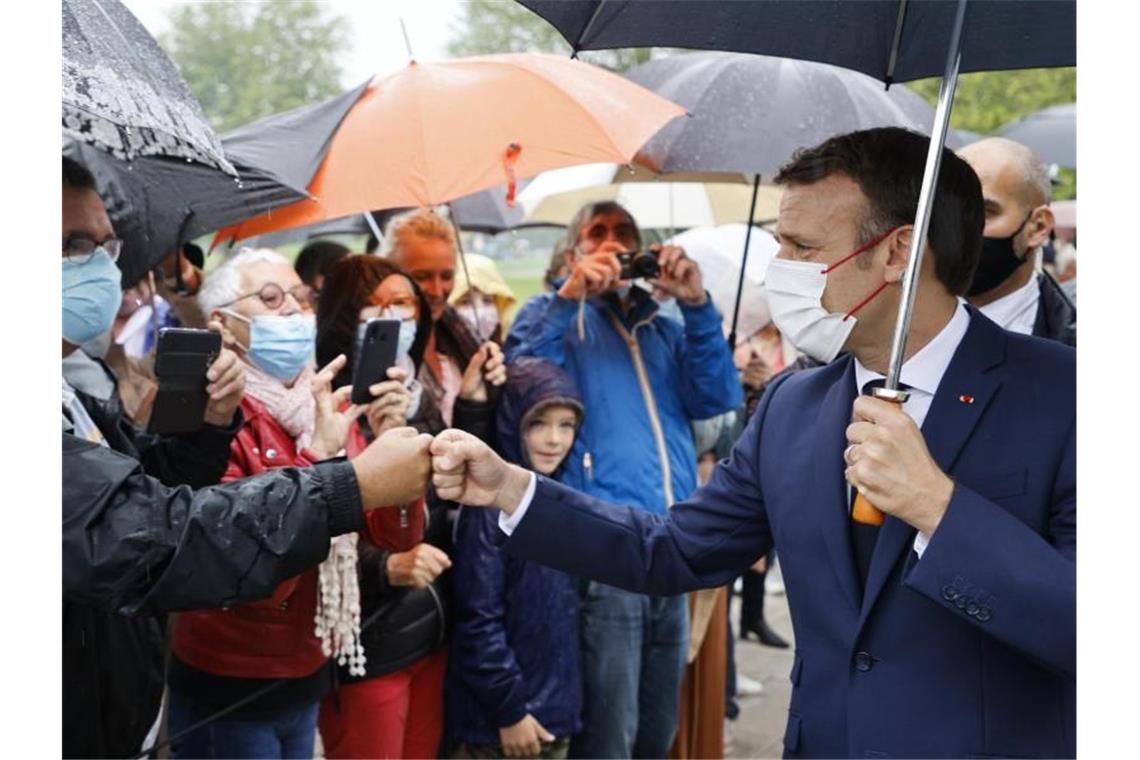 Emmanuel Macron (r), Präsident von Frankreich, begrüßt Anwohner bevor er seine Stimme in einem Wahllokal abgibt. Foto: Ludovic Marin/POOL AFP/AP/dpa