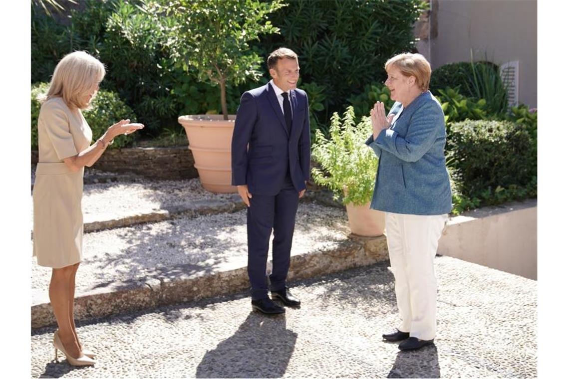 Emmanuel Macron und seine Frau Brigitte (l) begrüßen Bundeskanzlerin Angela Merkel bei ihrer Ankunft in der Sommerresidenz Macrons. Foto: Michael Kappeler/dpa