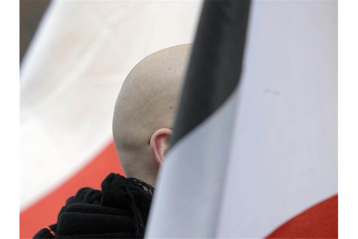 En Mann mit geschorenem Kopf zwischen schwarz-weiß-roten Fahnen: Momentaufnahme einer Demo. Foto: picture alliance / dpa