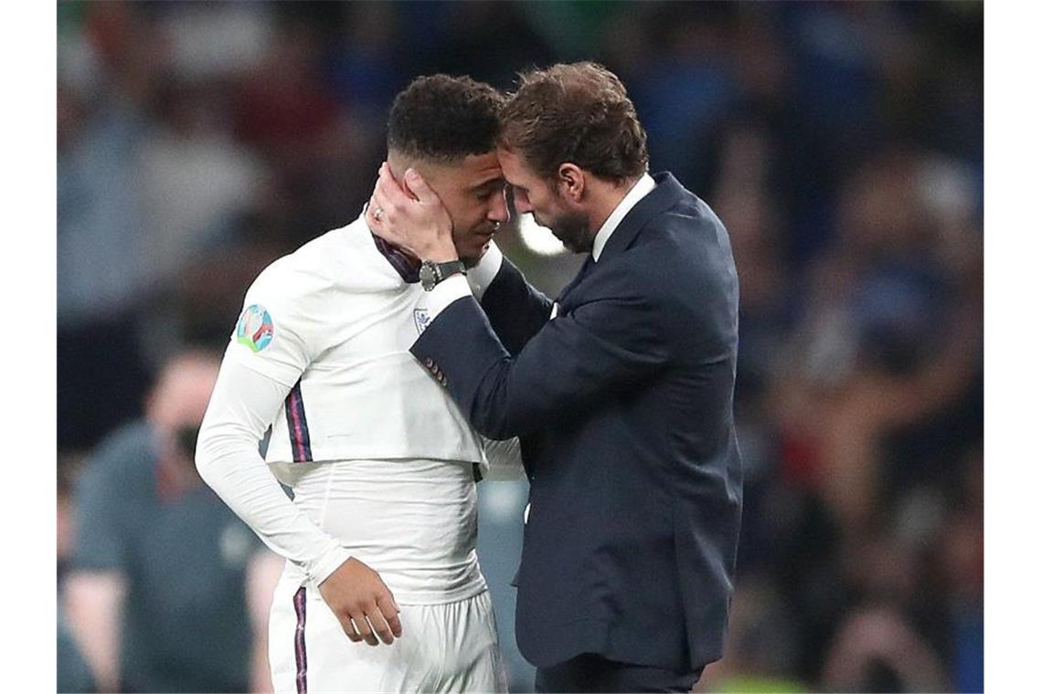 Rassistische Beleidigungen schocken England England-Coach Gareth Southgate spendet Trost für Jadon Sancho nach dessen verschossenen Elfmeter. Foto: Nick Potts/PA Wire/dpa