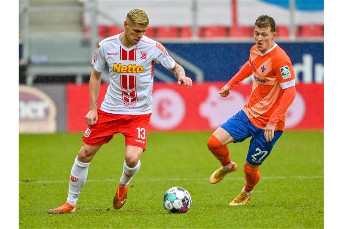 Erik Wekesser von Jahn Regensburg (l) kämpft mit Tim Skarke von Darmstadt 98 um den Ball. Foto: Armin Weigel/dpa