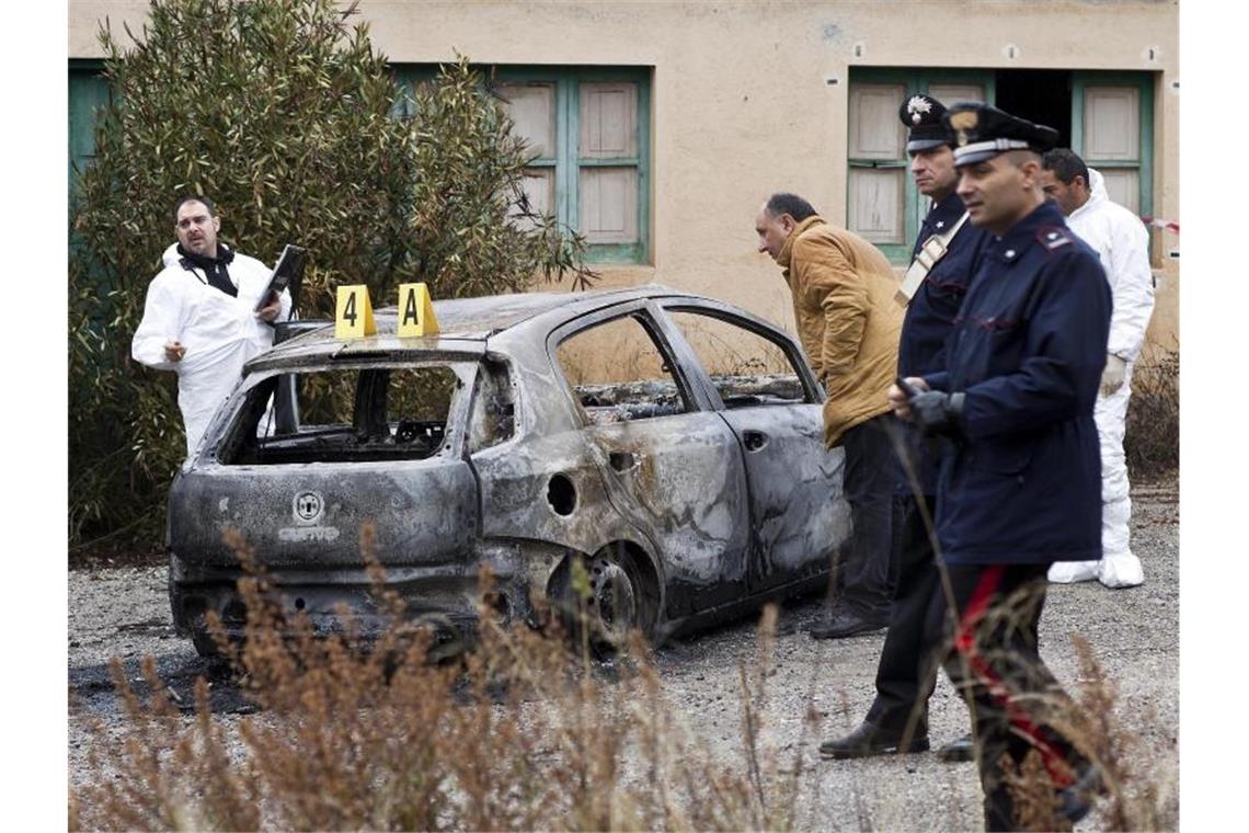 Ermittler arbeiten an einem verbrannten Auto, in dem drei verbrannte Leichen in Cassano allo Ionio, Provinz Kalabrien, Süditalien, gefunden wurden. Der Anschlag wird der 'Ndrangheta zugeordnet. Foto: Francesco Arena/ANSA/EPA/dpa