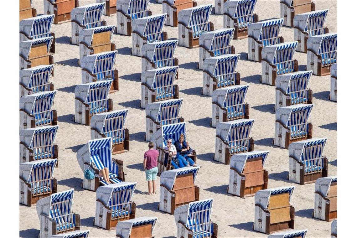 Erste Urlauber sitzen in Strandkörben am Ostseestrand in Warnemünde. Foto: Jens Büttner/dpa-Zentralbild/dpa