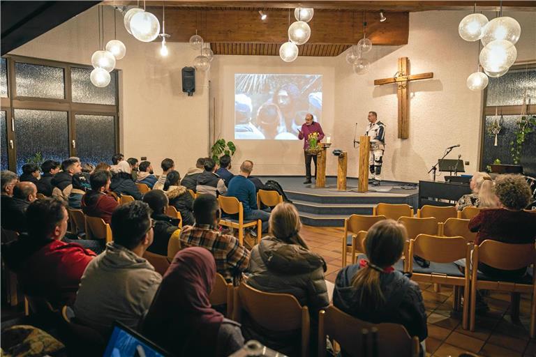 Erwin Häcker (auf der Bühne links) spricht beim Treff 18 über eine biblische Geschichte, Kamal Jolo übersetzt. Foto: Alexander Becher