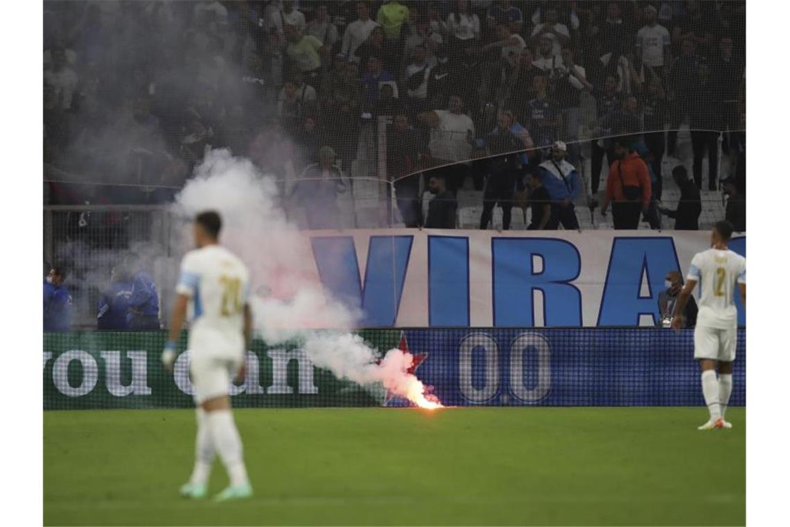 Es wurden auch Feuerwerkskörper auf Fans geschleudert. Andere Brandobjekte erreichten das Spielfeld. Foto: Daniel Cole/AP/dpa