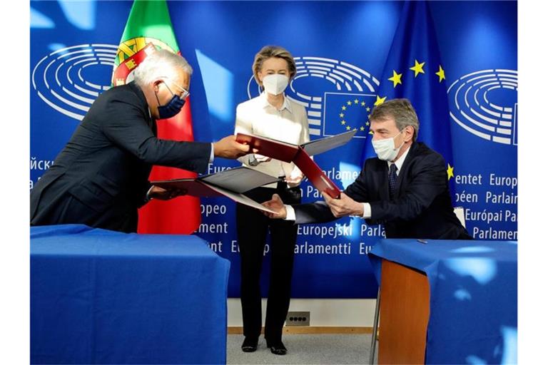 EU-Kommissionspräsidentin Ursula von der Leyen (M), schaut dabei zu, wie Portugals Premierminister Antonio Costa und EU-Parlaments-Präsident David Sassoli den Corona-Wiederaufbauplan unterzeichnen. Foto: Olivier Matthys/Pool AP/dpa