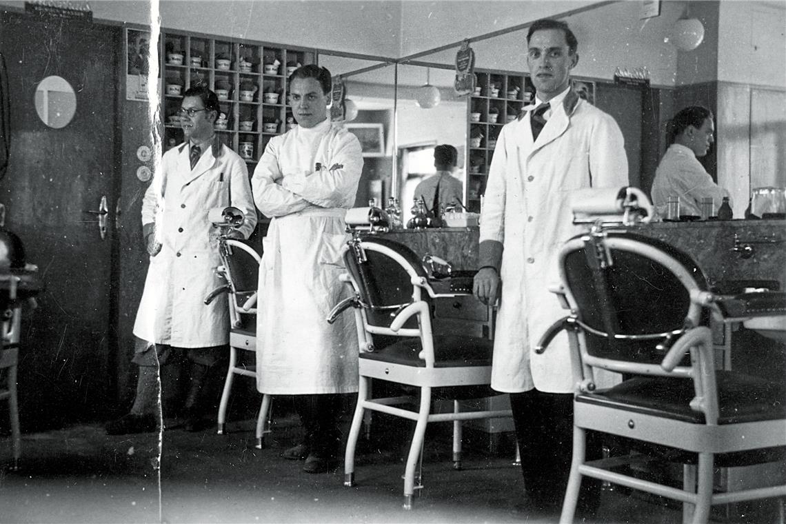 Ein Herrenfriseur mit Puppenklinik Eugen Kübler (links) mit zwei Gesellen um 1935. Das Regal im Hintergrund wurde bei Umbauarbeiten 2004 wiederentdeckt.