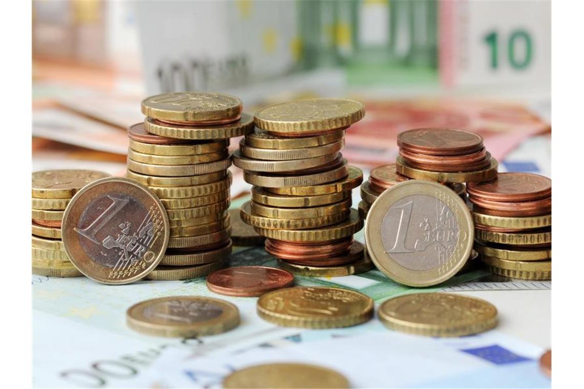 Land zahlt Fördergelder für ÖNPV früher aus Euro-Münzen auf Euro-Banknoten. Foto: Tobias Hase/dpa/Symbolbild