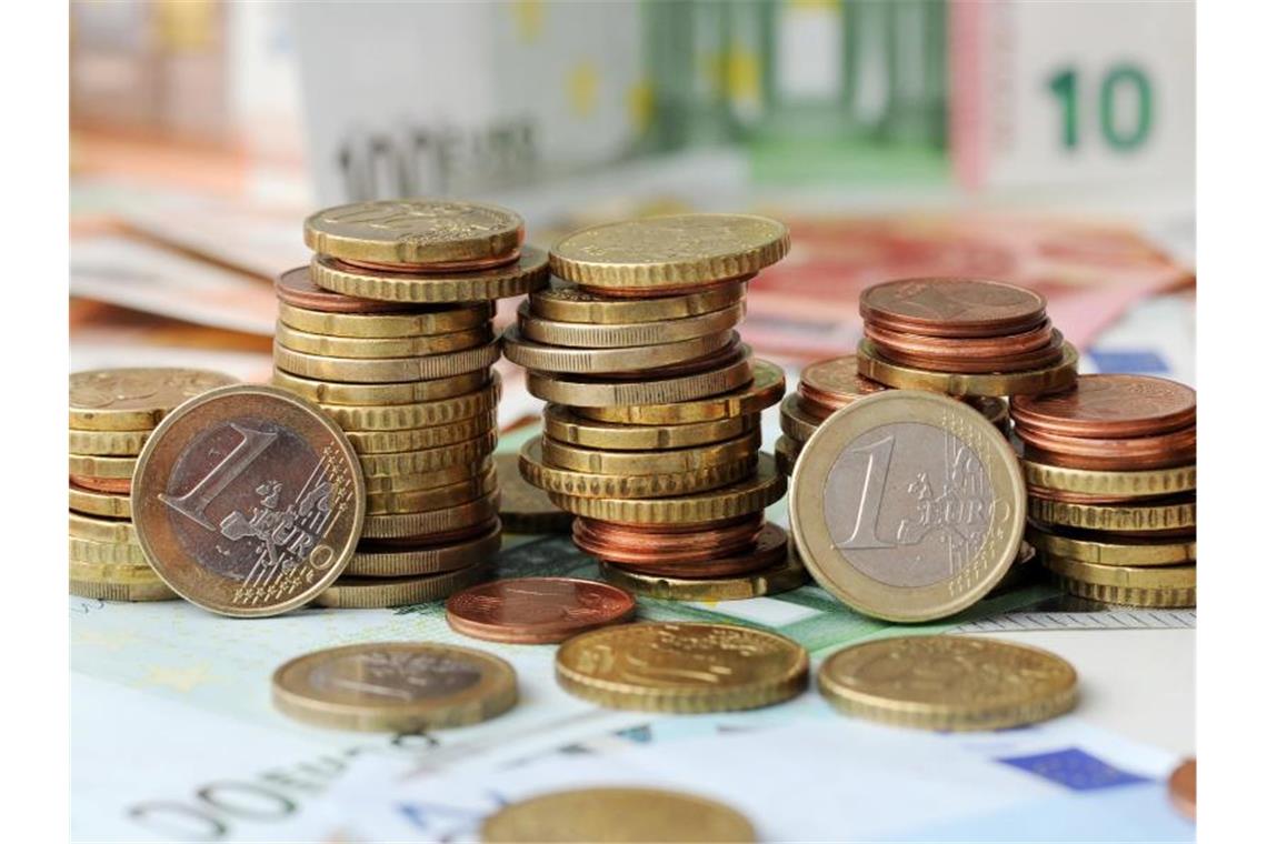 Erste Unternehmen erhalten schon Corona-Soforthilfe Euro-Münzen auf Euro-Banknoten. Foto: Tobias Hase/dpa/Symbolbild