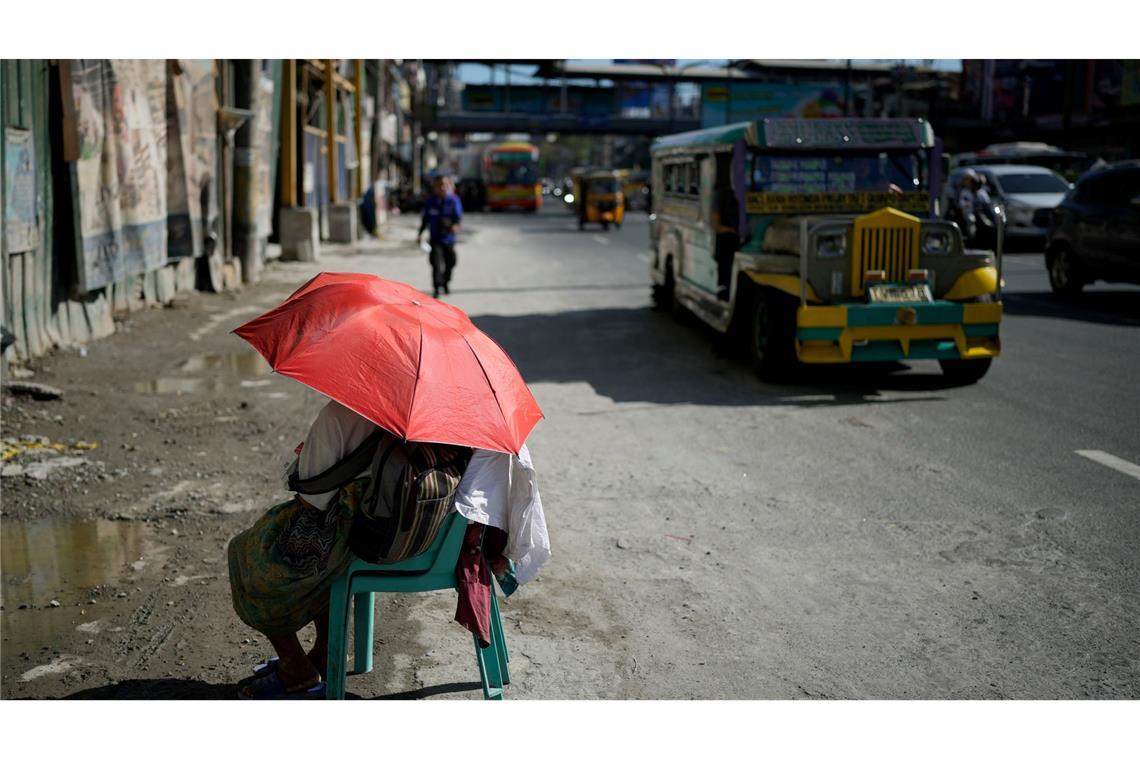 Extreme Hitze in den Straßen von Manila: Eine Verkäuferin schützt sich mit einem Regenschirm vor der Sonne. Auf den Philippinen und in weiteren südostasiatischen Ländern herrschen Rekordtemperaturen von gefühlt über 50 Grad.