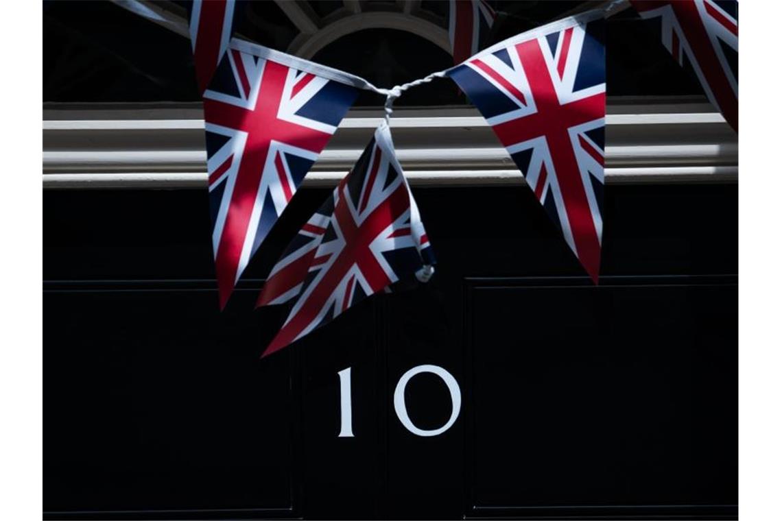 Fähnchen vor der Tür der 10 Downing Street. Aus Protest gegen das Verhalten des britischen Regierungsberaters Cummings ist Staatssekretär Douglas Ross zurückgetreten. Foto: Aaron Chown/PA Wire/dpa