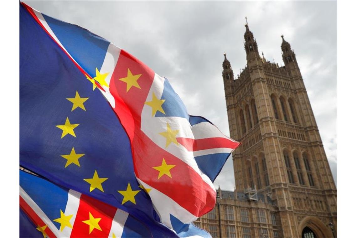 Brexit-Deal kostet britische Wirtschaft 70 Milliarden Pfund Fahnen wehen vor dem britischen Parlament. Foto: Alastair Grant/AP/dpa