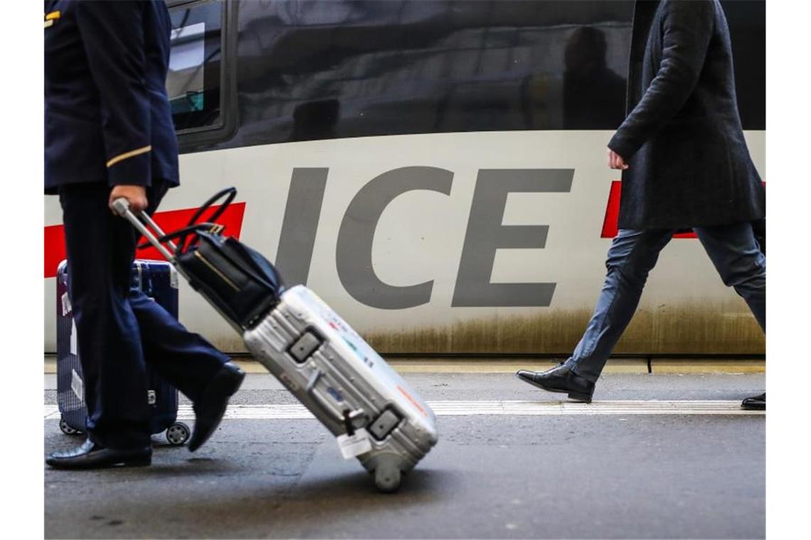 Zug schlägt Auto und Flugzeug beim klimafreundlichen Reisen Fahrgäste gehen mit ihrem Gepäck an einem ICE-Zug vorbei. Der Zug schlägt das Auto und das Flugzeug weiter beim klimafreundlichen Reisen. Foto: Christoph Schmidt/dpa