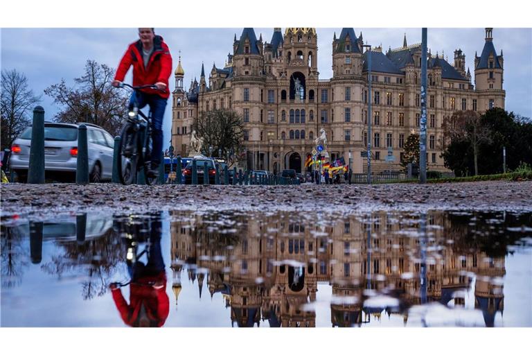 Fahrradfahrer vor dem Schweriner Schloss bei mildem, grauem Wetter in Norddeutschland.