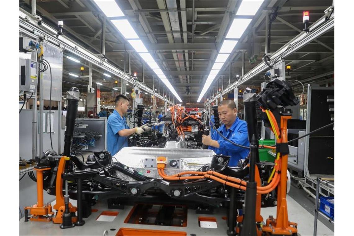 Fahrzeugbauer arbeiten in einer Werkshalle in Shanghai an einer Produktionslinie von SAIC Volkswagen. Foto: Ding Ting/XinHua/dpa