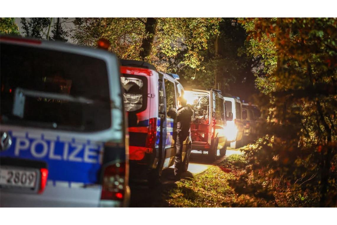 Fahrzeuge einer Einsatzhundertschaft der Polizei stehen in einem Waldgebiet in der Nähe des aufgefundenen Lastwagens des Tatverdächtigen.