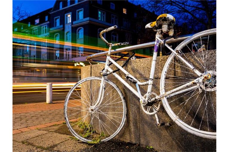 Fahrzeuge fahren an einem sogenannten „Ghost Bike“ vorbei, welches an einer Kreuzung in Hannover an einen tödlich verunglückten Fahrradfahrer erinnert. Foto: Moritz Frankenberg/dpa
