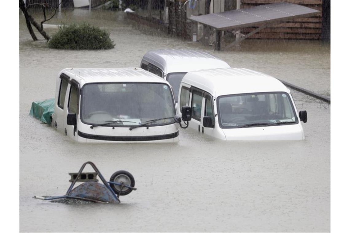 Fahrzeuge stehen in einem überfluteten Wohngebiet in der Präfektur Mie. Foto: ---/kyodo/dpa