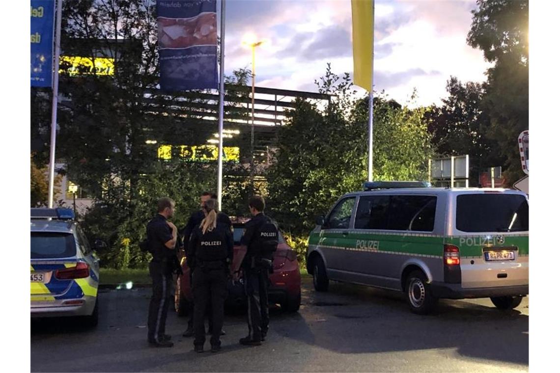 Fahrzeuge von Polizei und Feuerwehr stehen auf dem Parkplatz des Supermarktes in Abensberg. Ein 39 Jahre alter Mann ist aus ungeklärter Ursache erschossen worden. Foto: Alexander Auer/dpa