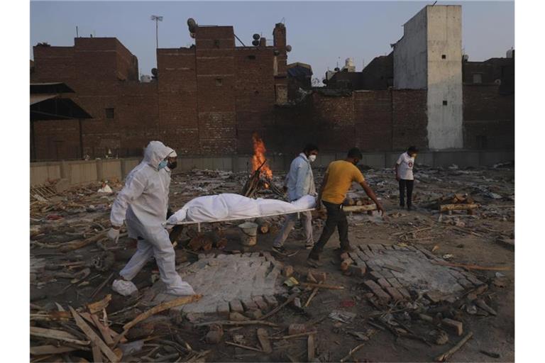 Familienmitglieder und Freiwillige tragen den Leichnam eines Corona-Opfers zur Einäscherung. Foto: Amit Sharma/AP/dpa/Archivbild