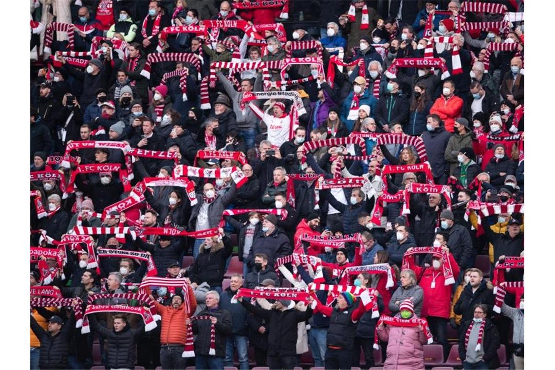 Lauterbach: „Spiele im vollen Stadion nicht akzeptabel“ Fans des 1. FC Köln halten Fanschals in die Luft. Foto: Marius Becker/dpa