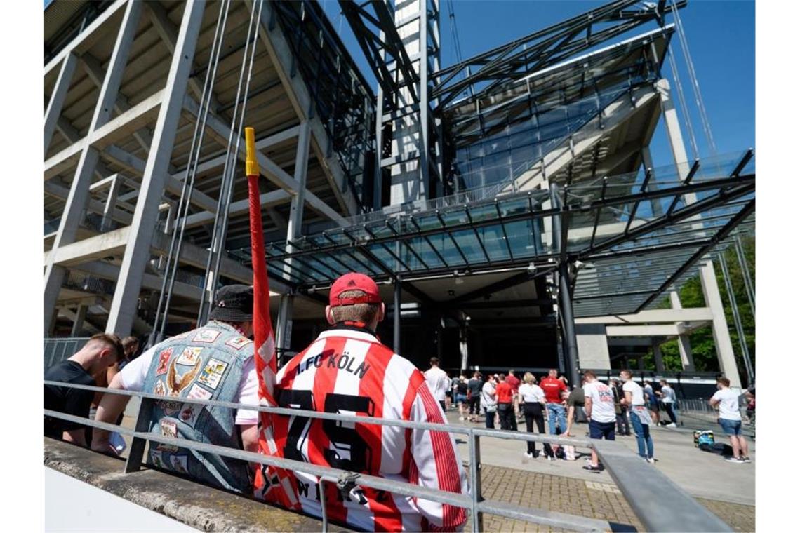 Für mehr Fans in den Stadien: Vereine klagen gegen ihr Land Fans des 1. FC Köln stehen vor dem RheinEnergie Stadion. Foto: Henning Kaiser/dpa
