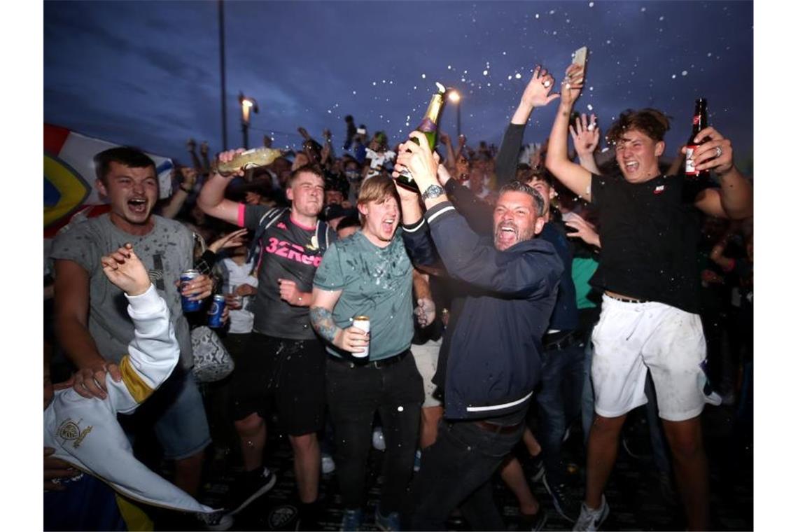 Fans des englischen Fußballclubs Leeds United jubeln vor dem Stadion in der Elland Road über den Aufstieg ihres Vereins. Foto: Nick Potts/PA Wire/dpa