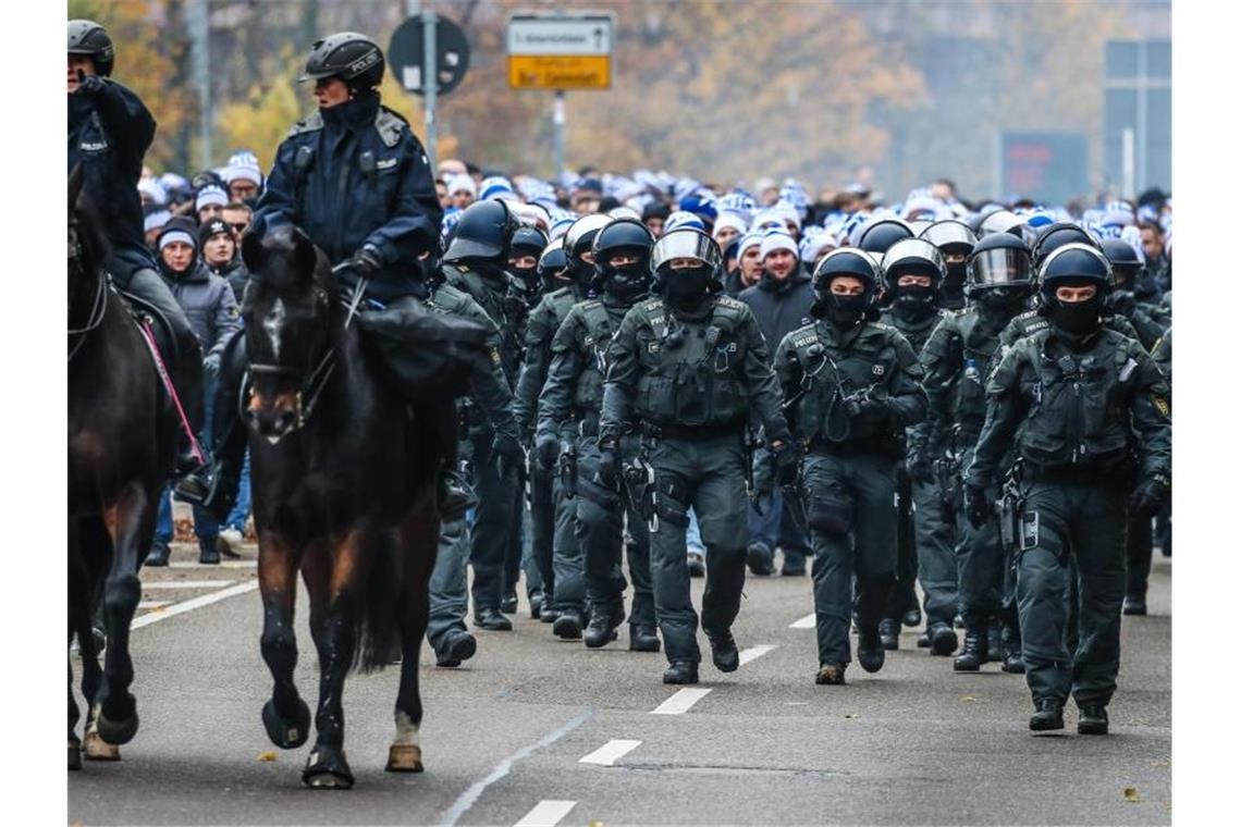 Fans vom Karlsruher SC gehen begleitet von der Polizei zur Mercedes-Benz Arena. Foto: Christoph Schmidt/dpa