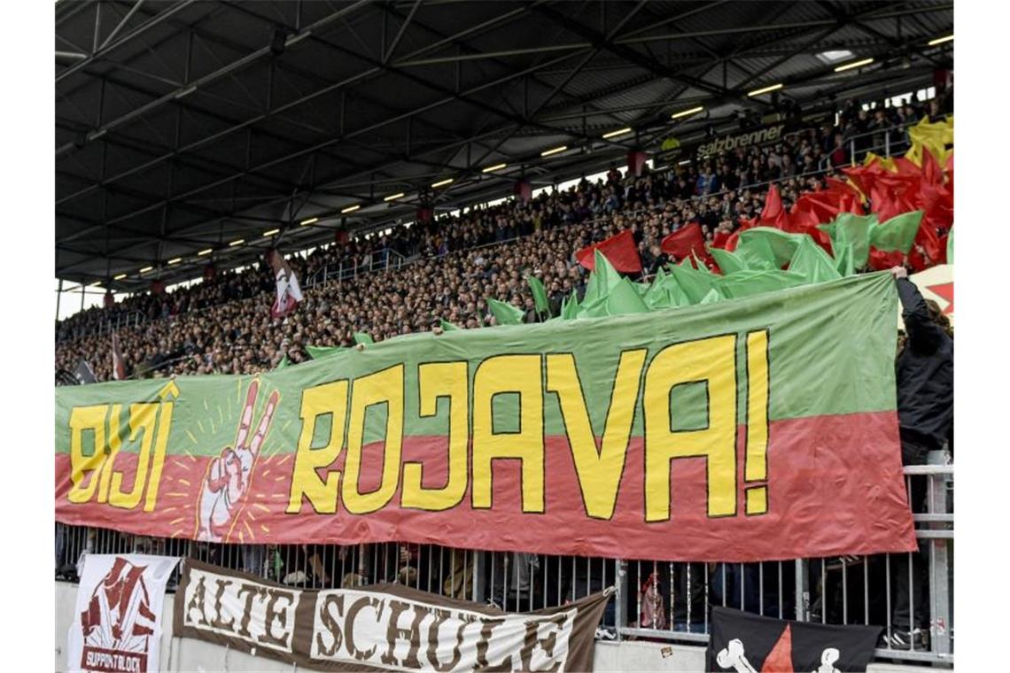 Fans von St. Pauli halten ein prokurdisches Banner mit dem Schriftzug „Biji Rojava“ („Es lebe Rojava“) in die Höhe. Foto: Axel Heimken/dpa