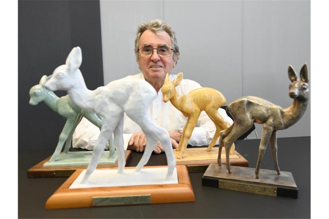 Fernsehproduzent Werner Kimmig sitzt hinter verschiedenen „Bambi“-Figuren. Foto: Patrick Seeger/dpa