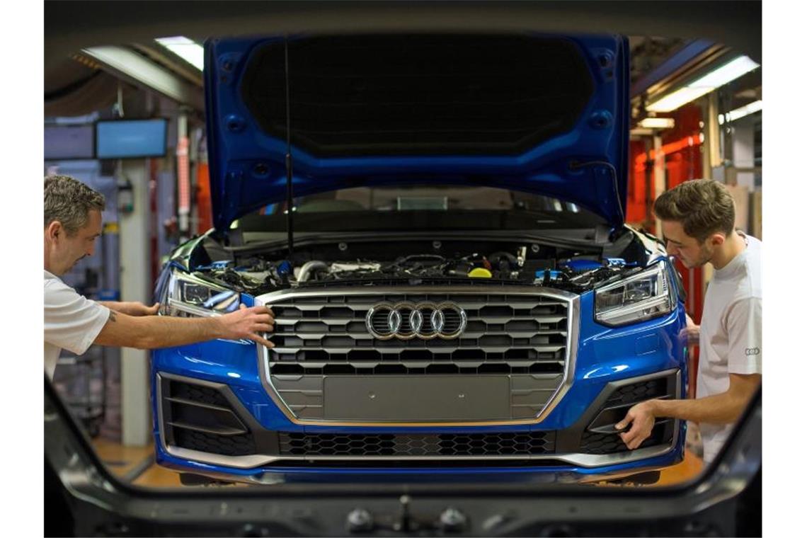 Fertigungsmechaniker bringen an einem Fließband im Audi-Werk die Front an einem Audi an. Foto: Andreas Gebert/dpa