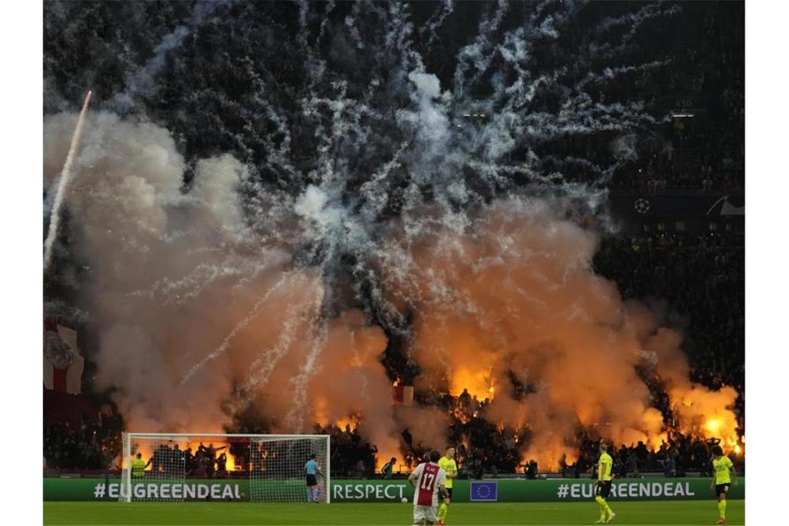Feuer und Rauch: Ajax-Fans zünden Feuerwerk während des Spiels. Foto: Peter Dejong/AP/dpa