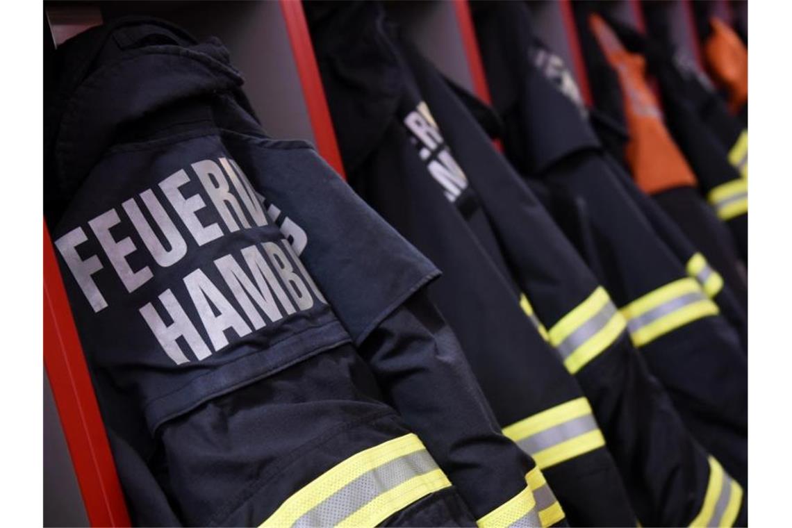 Feuerwehr-Einsatzjacken hängen in einer Feuerwache in Hamburg. Foto: picture alliance / Daniel Bockwoldt/dpa