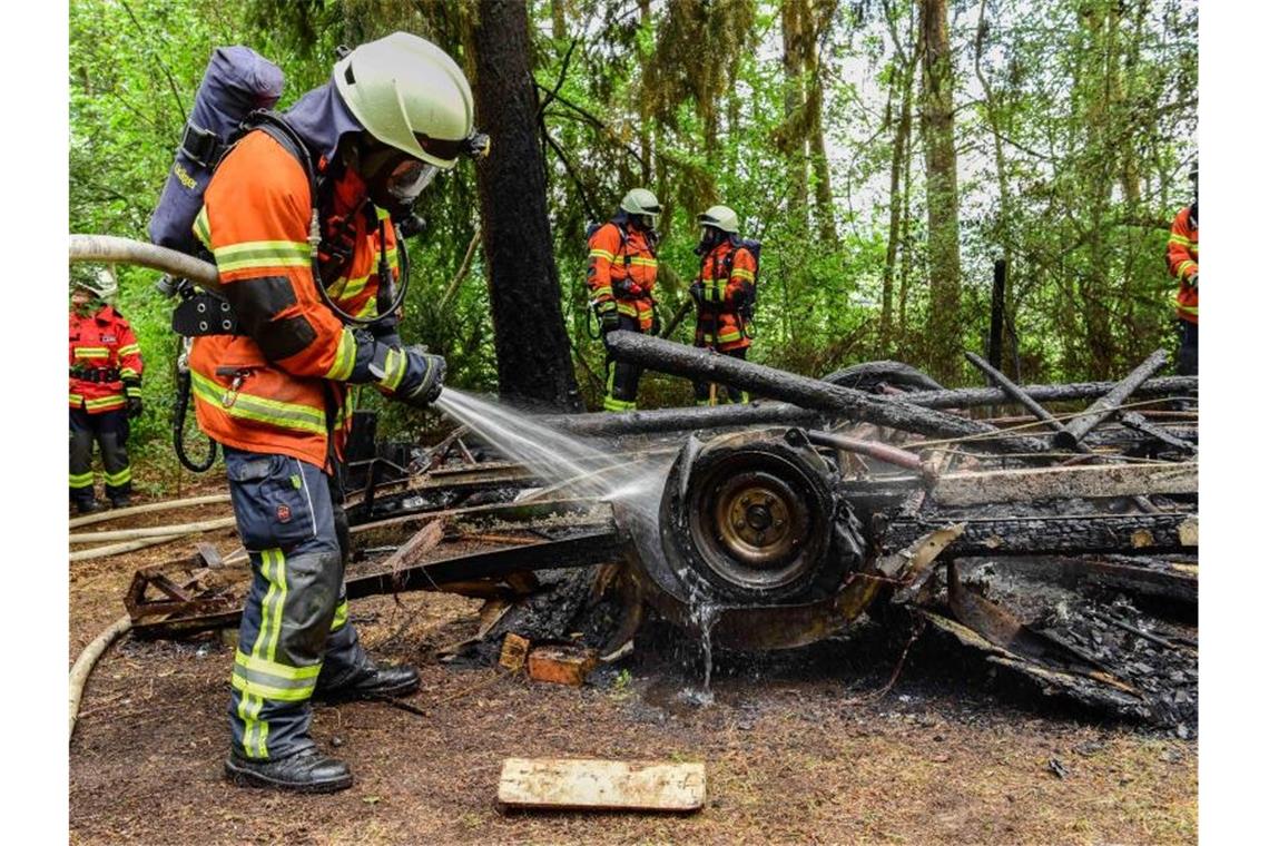 Feuerwehrkräfte löschen einen niedergebrannten Wohnwagen. Foto: Udo Zink/Kreisfeuerwehrverband Calw/dpa