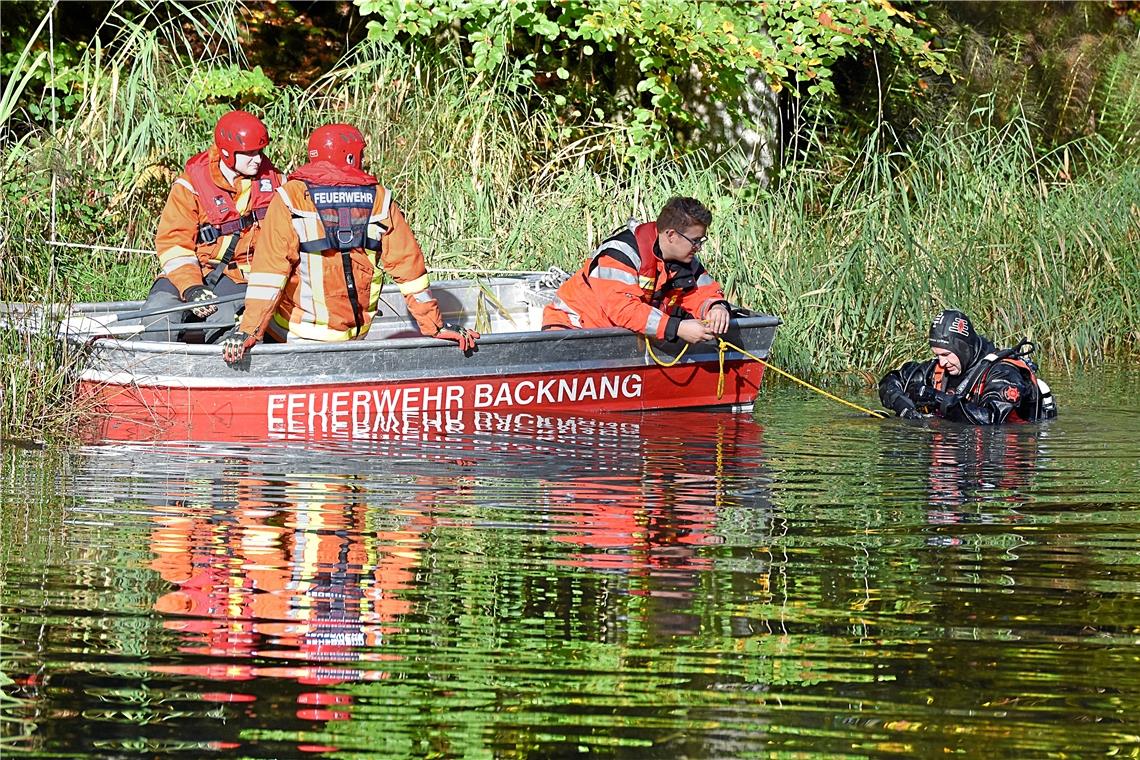 Feuerwehrkräfte und Taucher der DLRG suchen in einem Teich nach Ertrunkenen.
