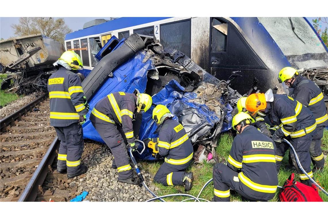 Feuerwehrleute arbeiten am Unglücksort, wo ein Personenzug und ein Lastwagen zusammengestoßen sind. Bei dem Unglück kam eine Person ums Leben, 21 Menschen wurden verletzt.