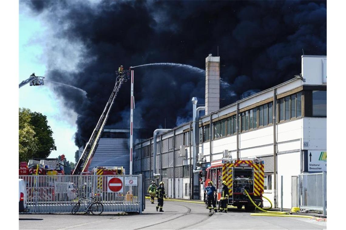 Feuerwehrleute auf Drehleitern löschen das Feuer in einer Kunststoff-Fabrik. Foto: Uwe Anspach/dpa