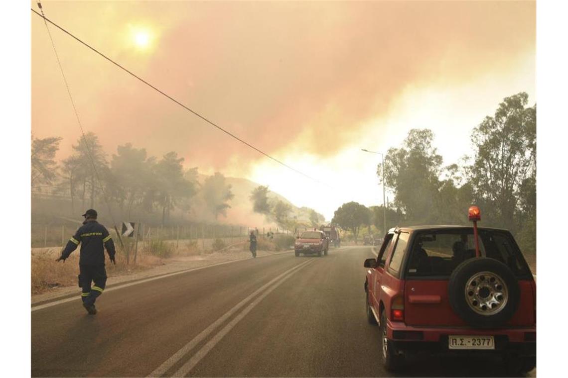 Feuerwehrleute bekämpfen einen Waldbrand in der Nähe des Dorfes Lampiri, westlich von Patras. Das an einem Berghang ausgebrochene Feuer hat sich in gefährlicher Nähe zu den Küstenstädten ausgebreitet. Foto: Andreas Alexopoulos/AP/dpa