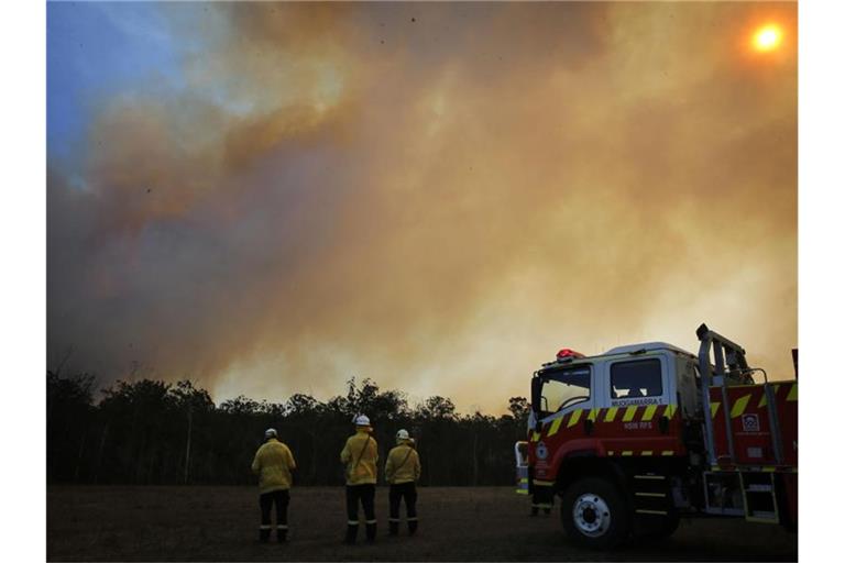 Feuerwehrleute beobachten im australischen Bundesstaat New South Wales die aus einem Waldgebiet aufsteigenden Rauchwolken. Foto: Darren Pateman/AAP/dpa