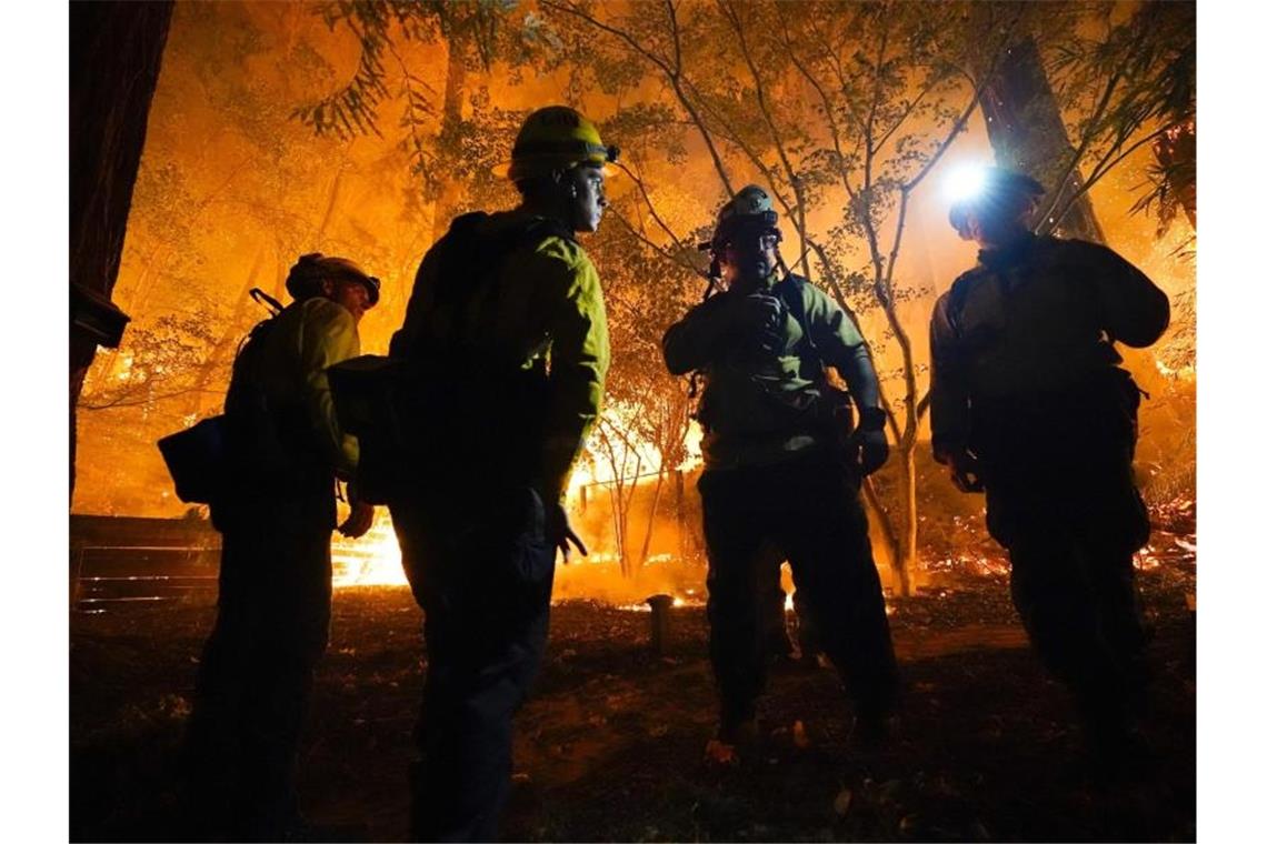 Feuerwehrleute besprechen das weitere Vorgehen bei Löscharbeiten. Foto: Marcio Jose Sanchez/AP/dpa
